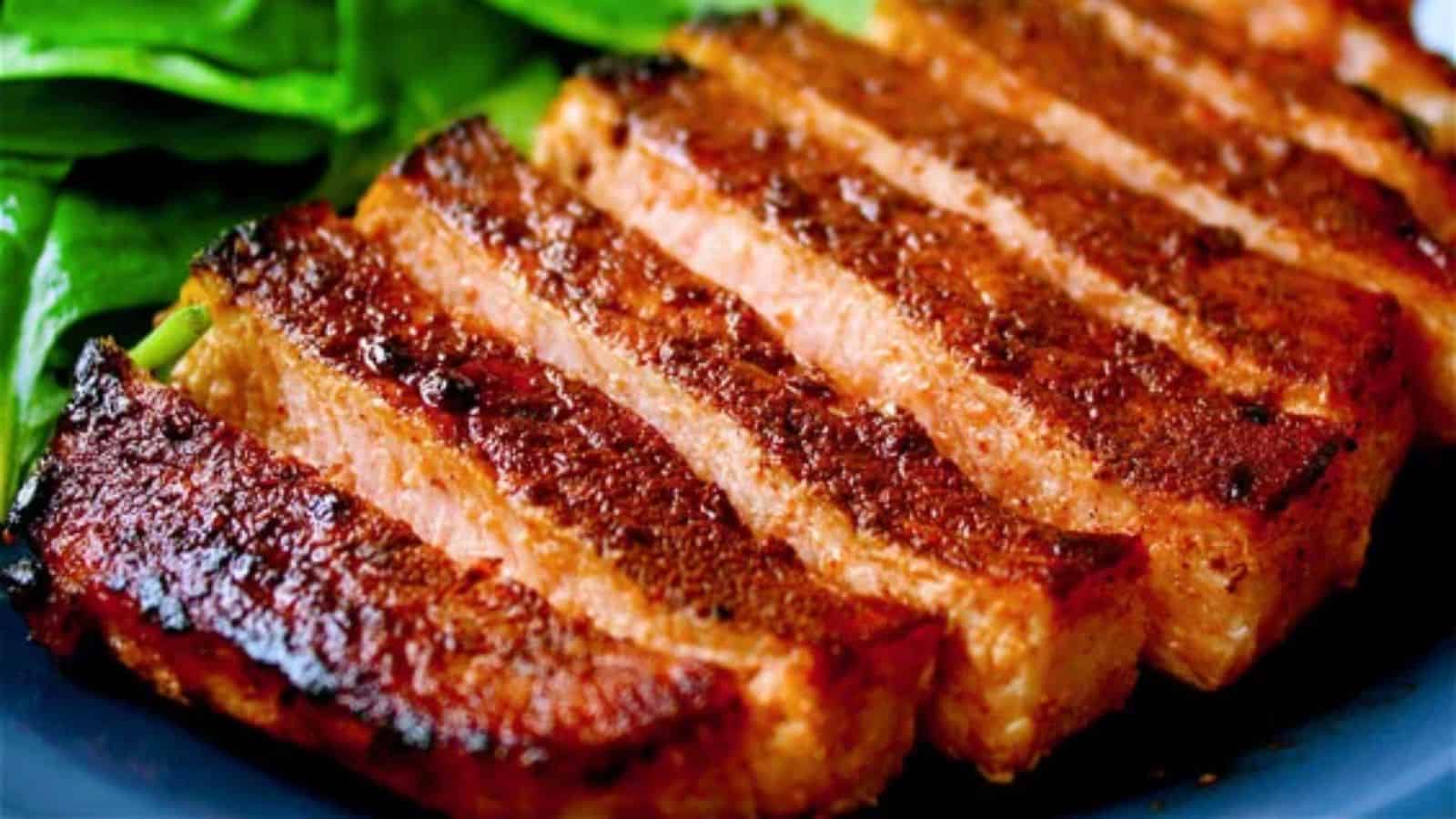 Close-up of perfectly grilled, smoky pork chops, sliced and resting on a bed of fresh green spinach.
