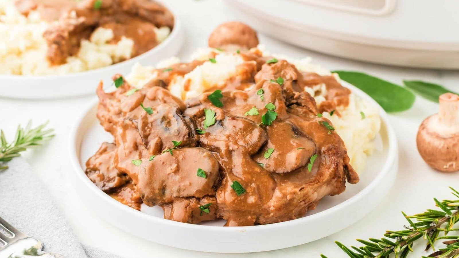 A plate of tender chicken in a creamy mushroom sauce, served over fluffy mashed potatoes, garnished with fresh parsley.