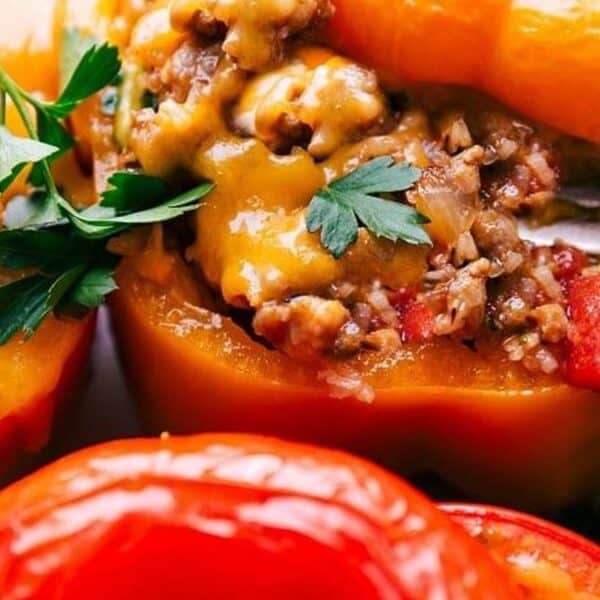 Close-up of stuffed bell peppers filled with ground beef and melted cheese, garnished with fresh parsley, with a fork taking a bite.