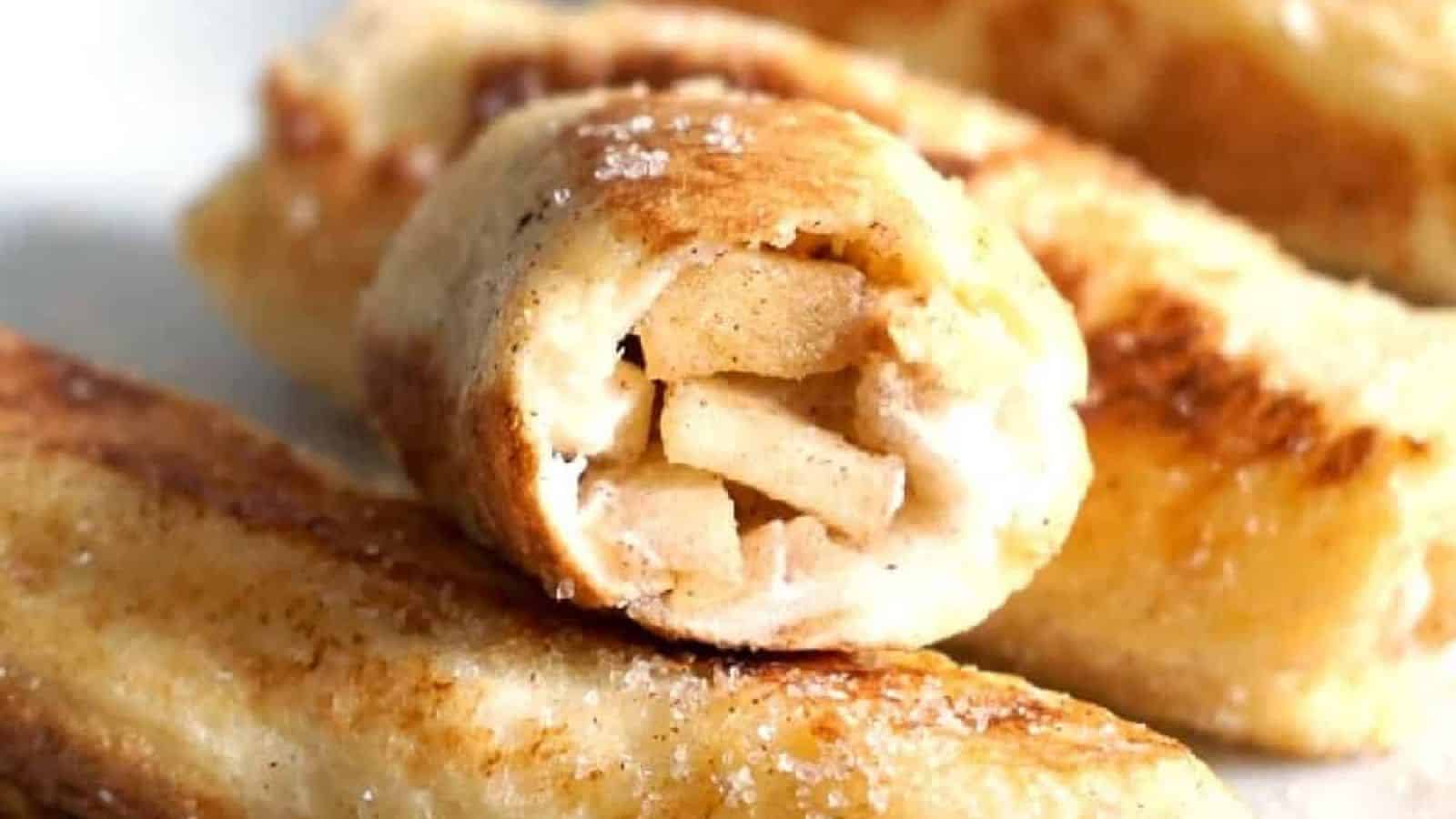 A rolled pastry filled with apple slices and cream, topped with sugar and cinnamon.
