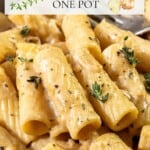 A close-up view of rigatoni pasta coated in a creamy sauce, topped with sprigs of fresh thyme. Overlaid text reads: "Creamy French Onion Rigatoni One Pot.