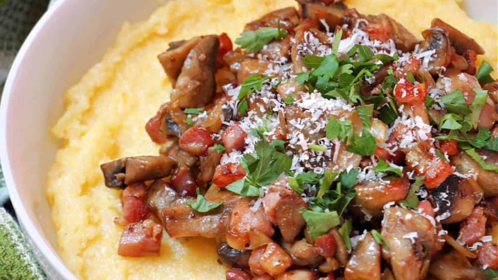 A bowl filled with creamy polenta, topped with sautéed mushrooms, diced tomatoes, grated cheese, and chopped fresh parsley.