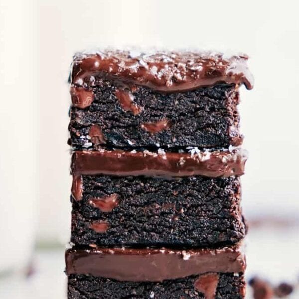 A stack of three chocolate brownies with chocolate frosting between each layer, topped with shredded coconut.
