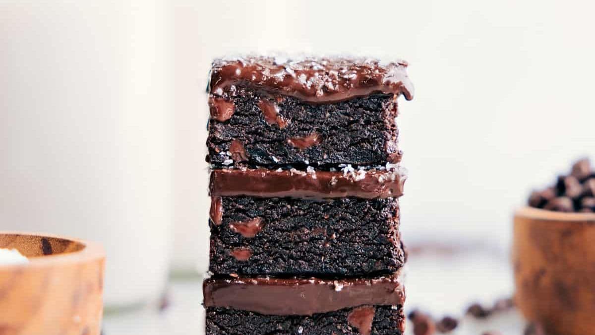 A stack of three chocolate brownies with chocolate frosting between each layer, topped with shredded coconut.