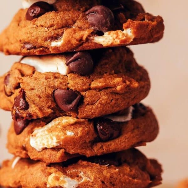 A stack of chocolate chip cookies with visible chunks of marshmallow, set against a blurred background.