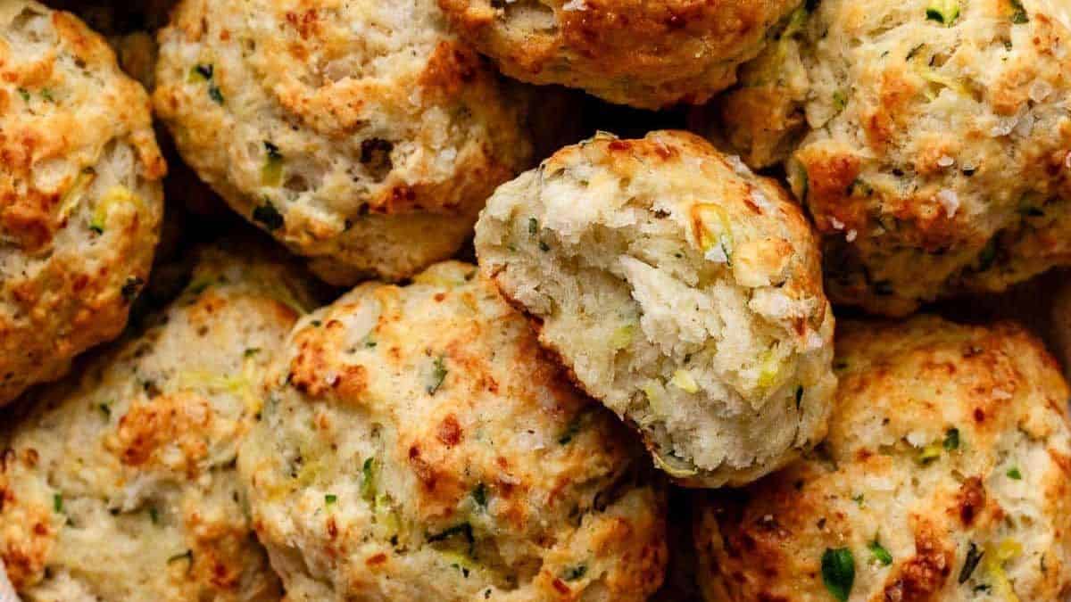 Several golden-brown biscuits with herbs, one split open to reveal a soft interior.