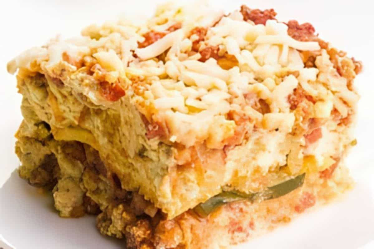 A slice of lasagna showing layers of pasta, melted cheese, ground meat, and tomato sauce on a white plate.