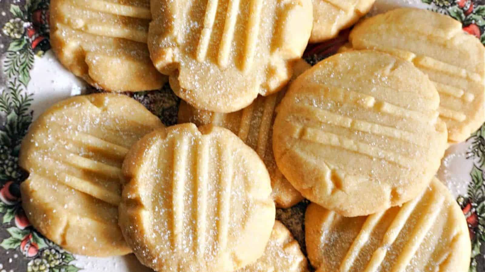 A plate with round, golden cookies featuring fork marks on top and a light dusting of sugar.