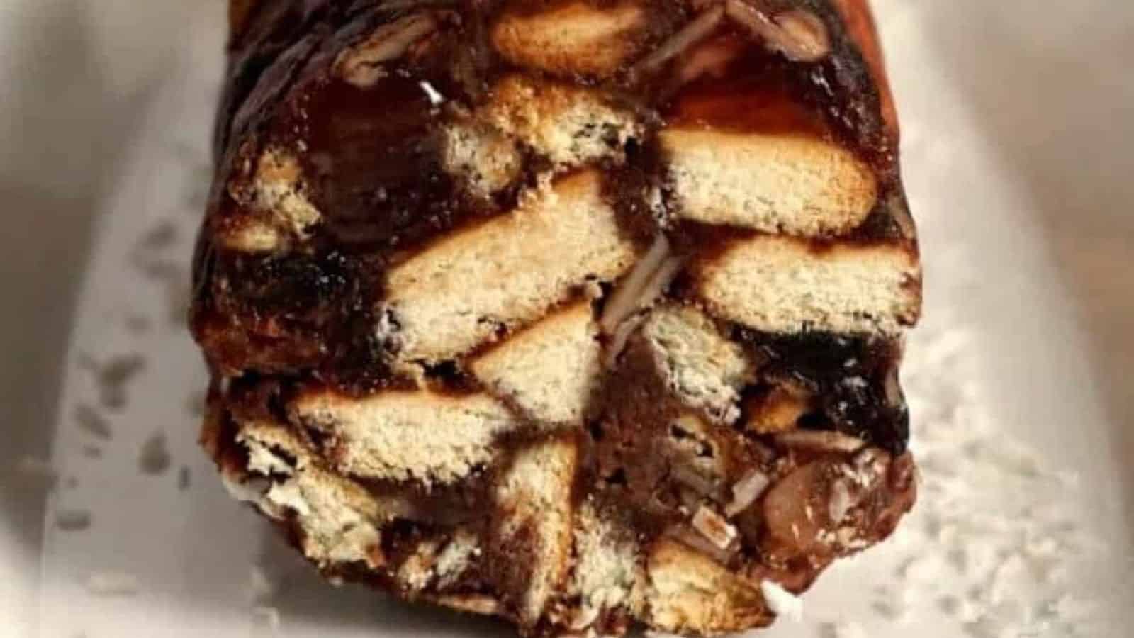 A close-up view of a slice of cake with pieces of biscuit visible inside a dense chocolate layer.