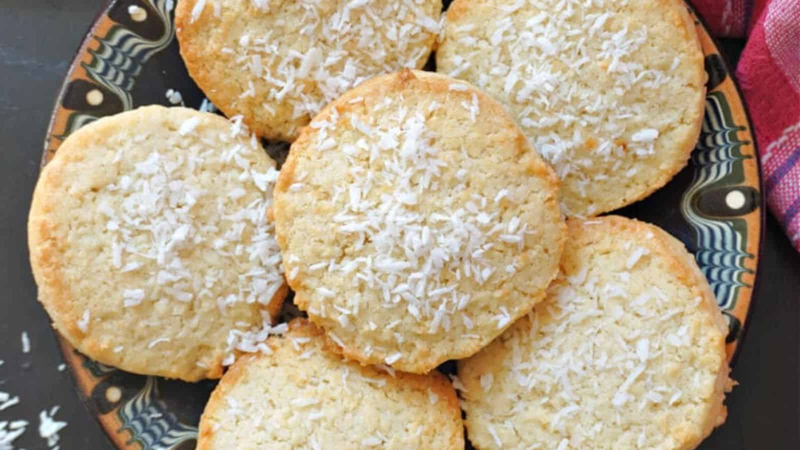 Seven round coconut cookies topped with shredded coconut, arranged in an overlapping pattern on a plate.