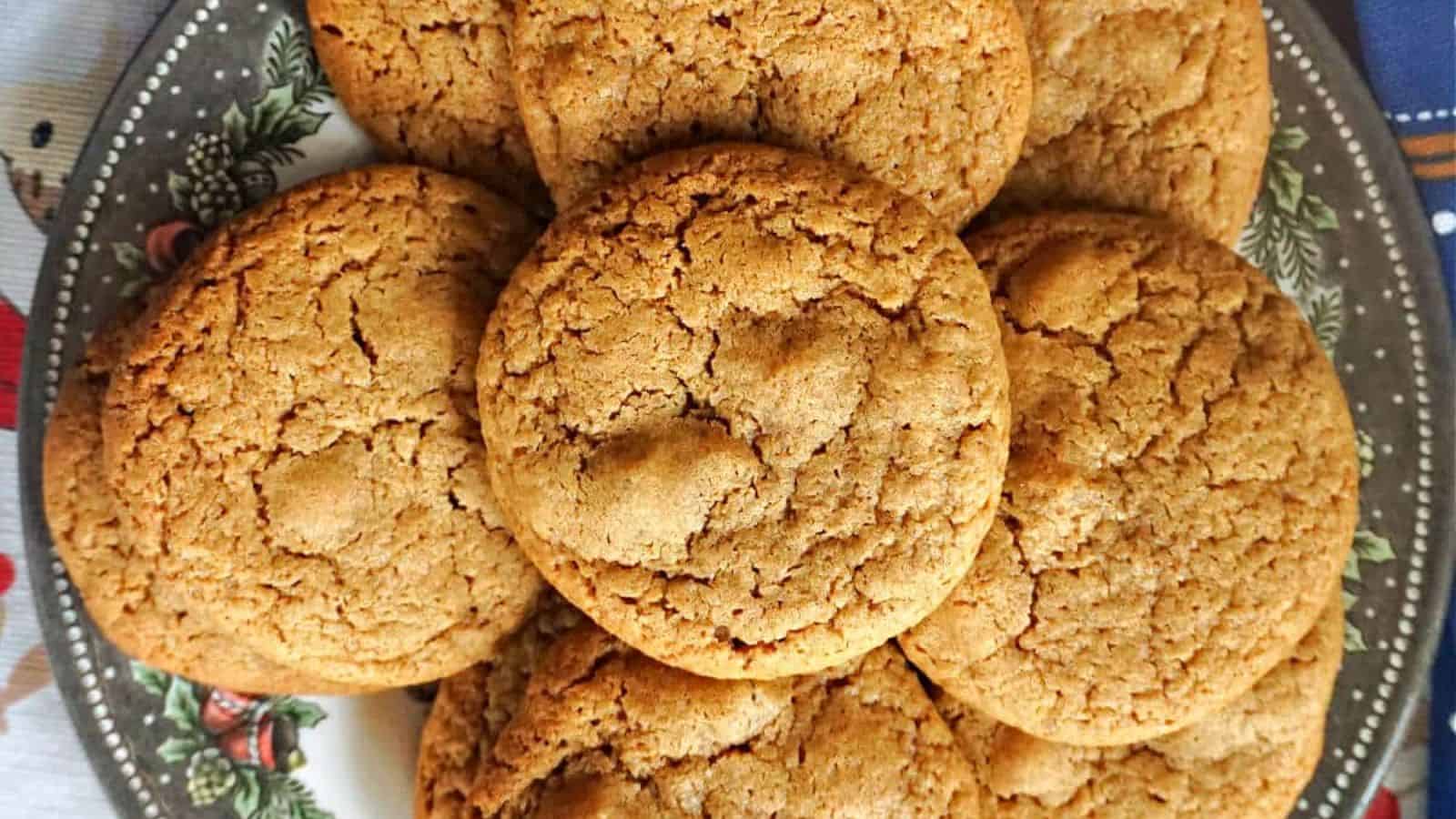 A plate piled with round, golden brown cookies featuring a cracked surface.