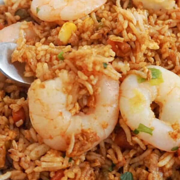 A bowl of shrimp fried rice with visible shrimp, peas, carrots, and a fork inside.