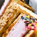Waffle ice cream sandwiches made with vanilla wafers, some coated in chopped nuts and others in colorful sprinkles.