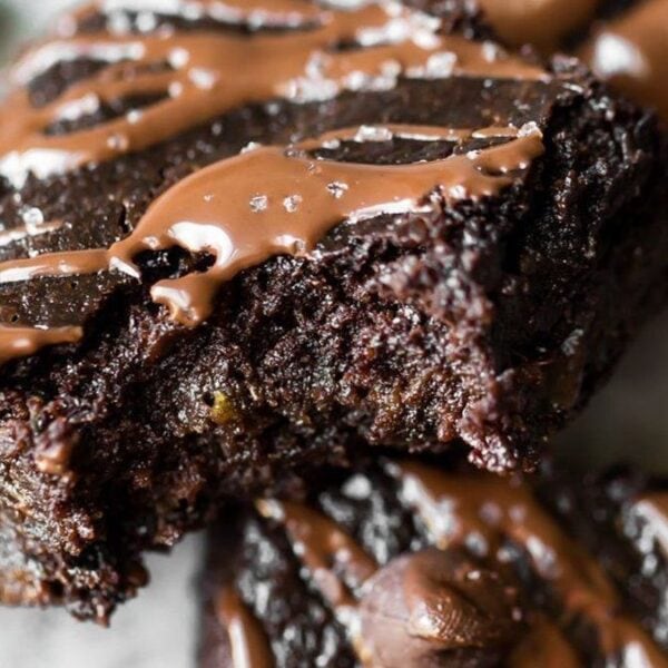A bitten chocolate brownie, drizzled with melted chocolate and sprinkled with coarse salt.