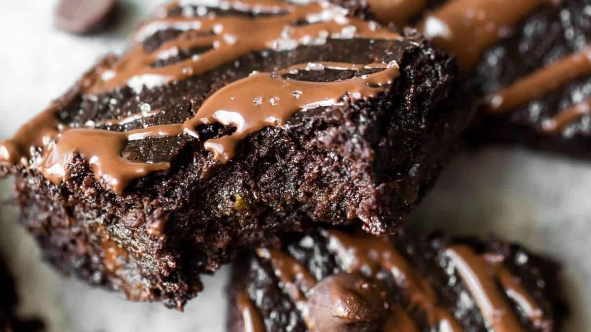 A bitten chocolate brownie, drizzled with melted chocolate and sprinkled with coarse salt.