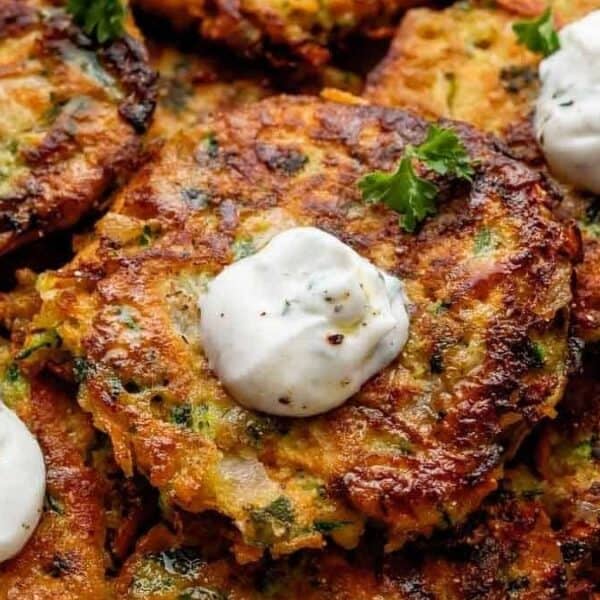 Golden-brown vegetable fritters topped with sour cream and sprinkled with fresh herbs.