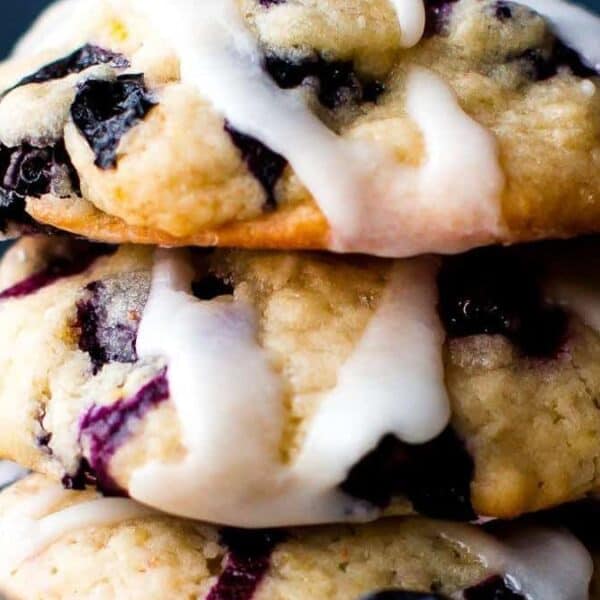 Three blueberry cookies stacked on top of each other, each drizzled with white icing.