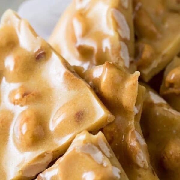Several pieces of peanut brittle with a glossy, golden-brown surface and embedded peanuts.
