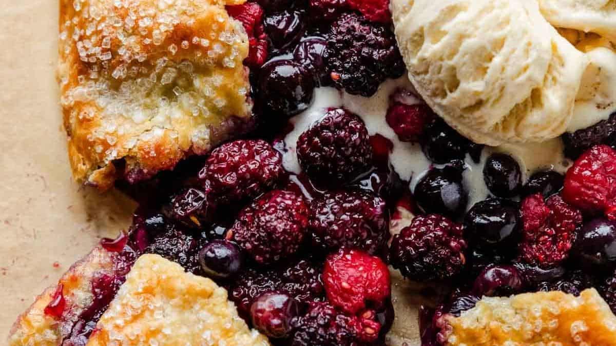 A golden, sugared pastry crust filled with mixed berries and topped with a scoop of vanilla ice cream.