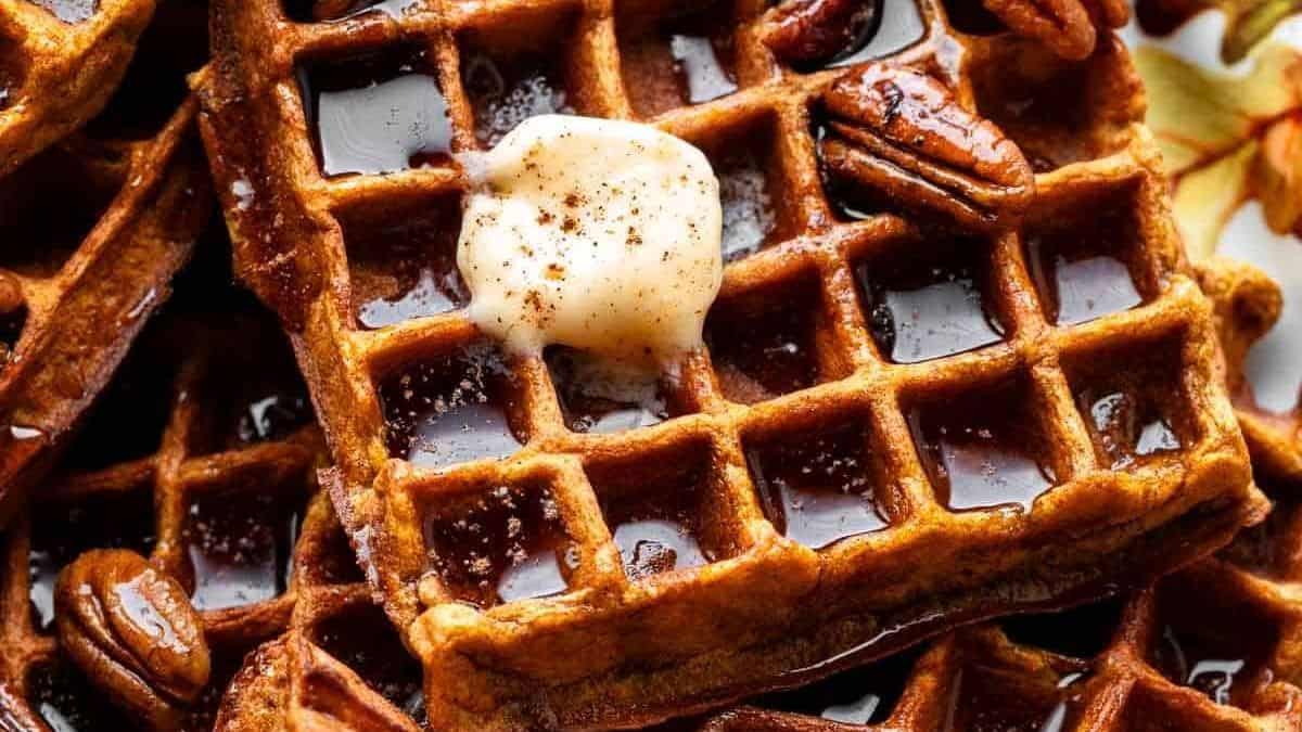 Waffles with a pat of butter, pecans, and syrup on top.