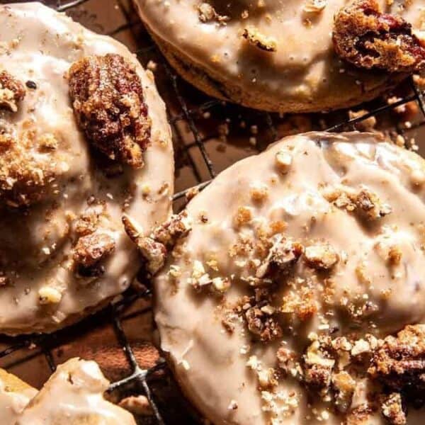 Iced cookies with chopped candied pecans rest on a metal wire rack.
