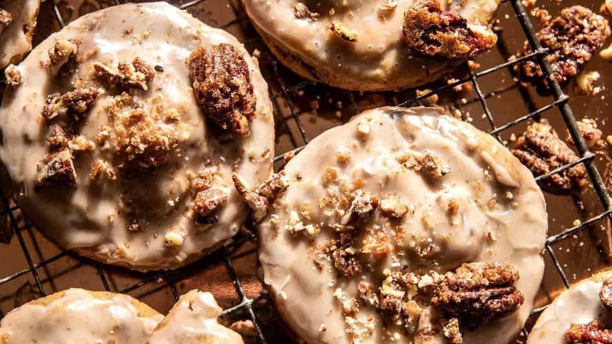 Iced cookies with chopped candied pecans rest on a metal wire rack.