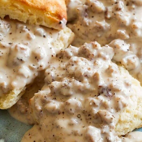 Biscuits topped with creamy sausage gravy are served on a blue patterned plate.