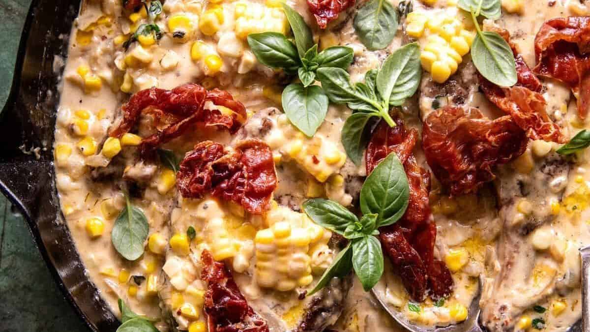 Corn, crispy prosciutto, fresh basil leaves, and a rich creamy sauce in a skillet.