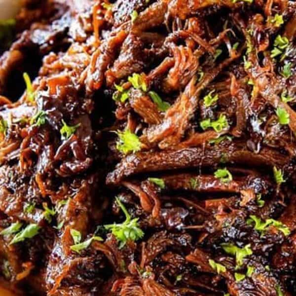Shredded beef topped with chopped parsley served in a white bowl.