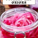 A glass jar of sliced pickled red onions on a wooden surface, with text reading "Sweet and Spicy Pickled Red Onions" and "Not Entirely Average.