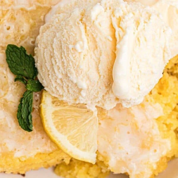 A bowl of lemon dessert topped with vanilla ice cream, garnished with a mint sprig and a lemon slice.