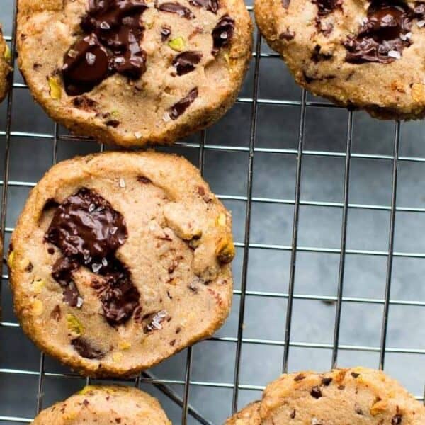 Chocolate chip cookies with visible chocolate chunks are cooling on a metal wire rack.