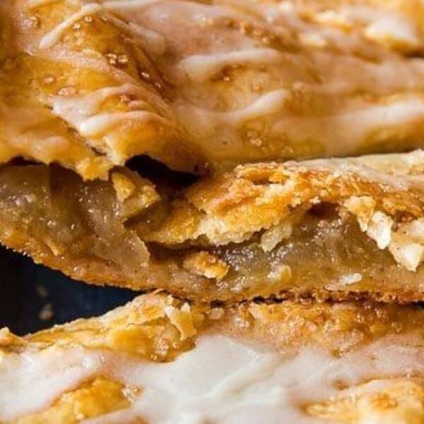 Close-up of sliced apple pie bars with a golden, flaky crust and a layer of white icing on top.
