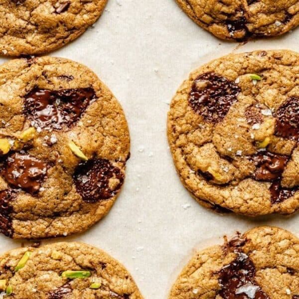Chocolate chip cookies with chocolate chunks and nut pieces on parchment paper.